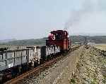 ‘Prince’ sets out along the Cob with a rake of slate waggons in the afternoon sun.   (01/05/2004)